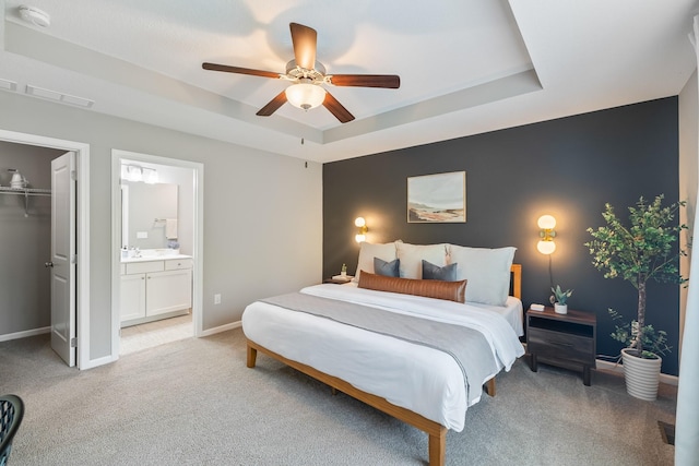 4315 E 48th St, Des Moines, IA 50317 - bedroom featuring light carpet, a spacious closet, connected bathroom, and a tray ceiling