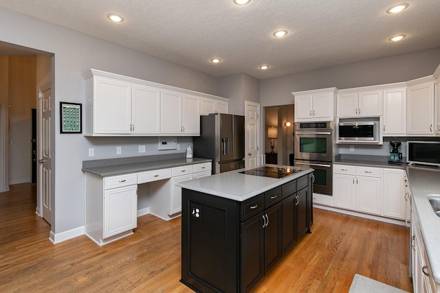 14092 Lake Pointe Dr, Clive, IA 50325 - kitchen with appliances with stainless steel finishes, white cabinets, dark cabinetry, a kitchen island, and light wood-style flooring
