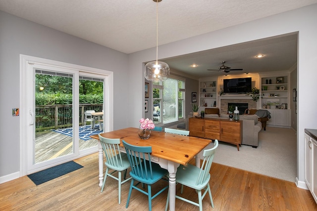 14092 Lake Pointe Dr, Clive, IA 50325 - dining area featuring a fireplace, light wood-style floors, ceiling fan, and healthy amount of natural light