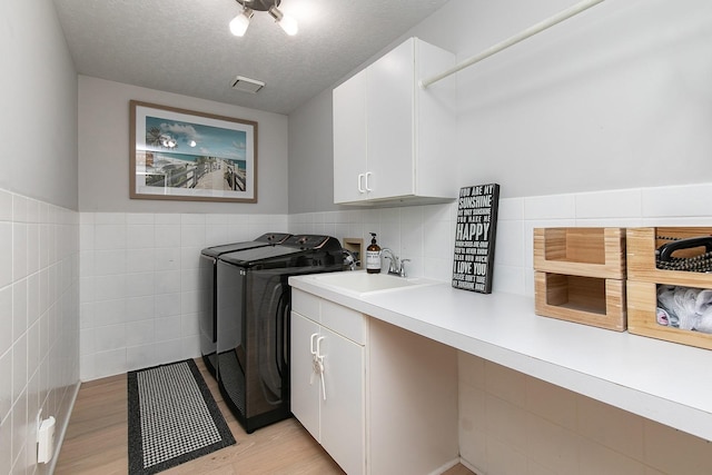 14092 Lake Pointe Dr, Clive, IA 50325 - laundry area with cabinet space, tile walls, washer and clothes dryer, light wood-type flooring, and wainscoting