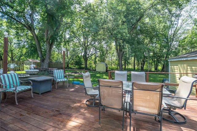 808 Bridge St, Redfield, IA 50233 - deck with outdoor dining space, a storage shed, a fenced backyard, and view of wooded area