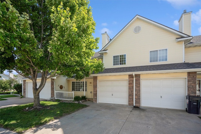 1517 SE Delaware Ave Unit 2, Ankeny, IA 50021 - view of front of house with driveway, a chimney, an attached garage, stone siding, and a shingled roof