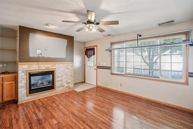 1517 SE Delaware Ave Unit 2, Ankeny, IA 50021 - unfurnished living room featuring a ceiling fan, a fireplace, wood finished floors, and a textured ceiling