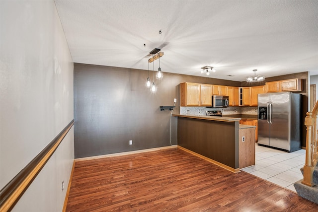 1517 SE Delaware Ave Unit 2, Ankeny, IA 50021 - kitchen with stainless steel appliances, a peninsula, light wood finished floors, backsplash, and glass insert cabinets