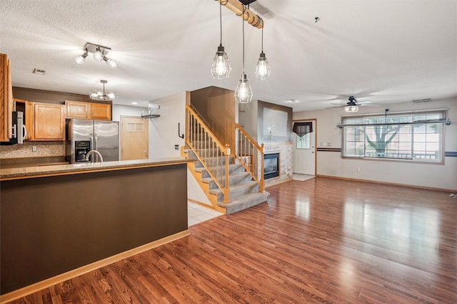 1517 SE Delaware Ave Unit 2, Ankeny, IA 50021 - kitchen with appliances with stainless steel finishes, a chandelier, a tiled fireplace, ceiling fan, and light wood finished floors