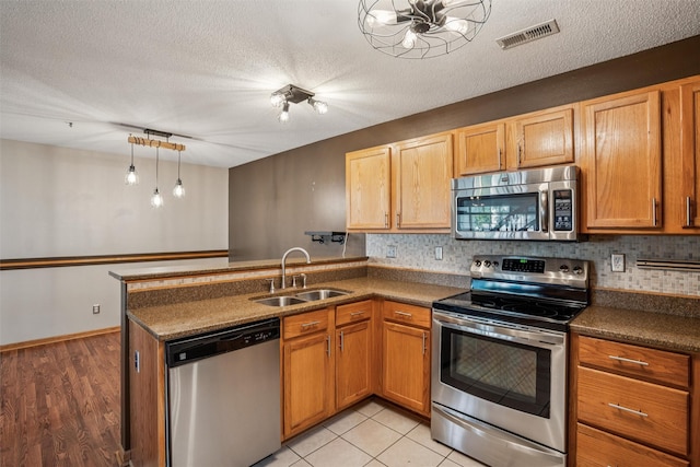 1517 SE Delaware Ave Unit 2, Ankeny, IA 50021 - kitchen with appliances with stainless steel finishes, a peninsula, dark countertops, decorative backsplash, and a textured ceiling