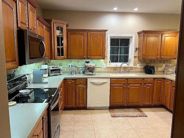 2279 Pheasant Ridge Ln, Ames, IA 50010 - kitchen with appliances with stainless steel finishes, decorative backsplash, glass insert cabinets, brown cabinets, and light countertops
