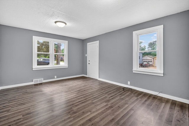 34 E Broadway St, Colfax, IA 50054 - empty room featuring healthy amount of natural light, dark wood-style flooring, and a textured ceiling