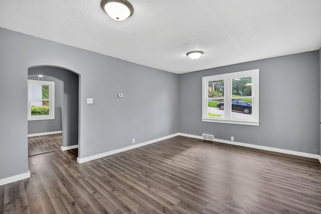 34 E Broadway St, Colfax, IA 50054 - empty room featuring arched walkways, dark wood finished floors, and a textured ceiling