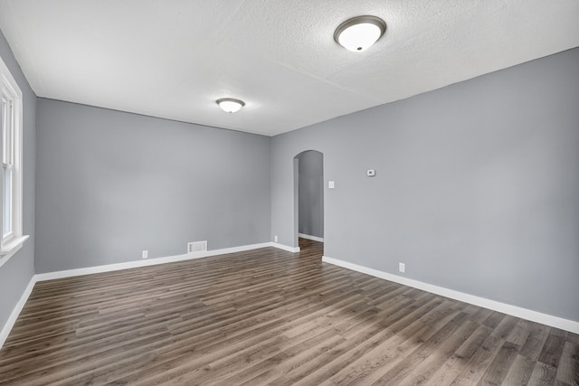 34 E Broadway St, Colfax, IA 50054 - spare room featuring arched walkways, dark wood finished floors, and a textured ceiling