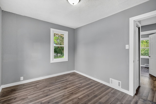 34 E Broadway St, Colfax, IA 50054 - empty room featuring healthy amount of natural light, dark wood-type flooring, and a textured ceiling