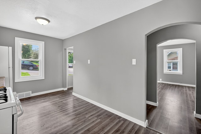 34 E Broadway St, Colfax, IA 50054 - unfurnished dining area with arched walkways, dark wood-style floors, and a textured ceiling