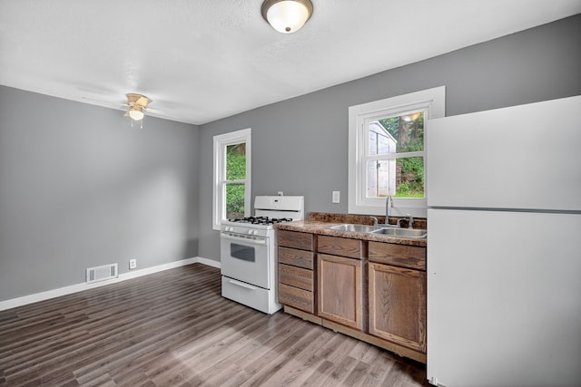 34 E Broadway St, Colfax, IA 50054 - kitchen with white appliances, light wood finished floors, ceiling fan, and brown cabinetry