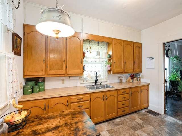 3917 11th St, Des Moines, IA 50313 - kitchen featuring backsplash, brown cabinets, and light countertops