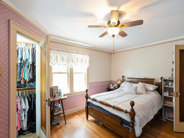 4987 E 28th St N, Newton, IA 50208 - bedroom featuring wood finished floors, ornamental molding, wallpapered walls, and a ceiling fan