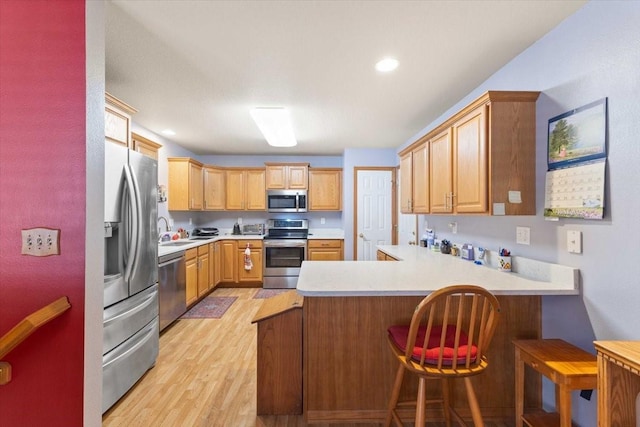 827 SW 46th St, Ankeny, IA 50023 - kitchen with appliances with stainless steel finishes, a peninsula, light wood finished floors, light countertops, and a kitchen breakfast bar