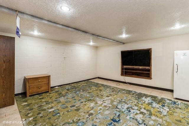 644 N 43rd St, Cumming, IA 50061 - finished basement featuring freestanding refrigerator, a textured ceiling, and concrete block wall