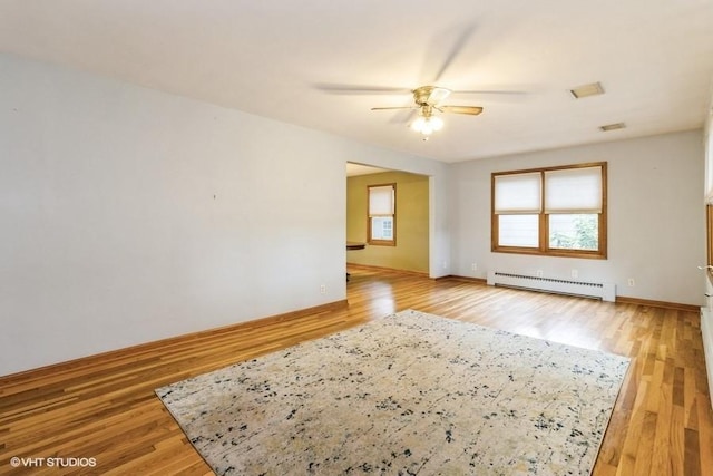 644 N 43rd St, Cumming, IA 50061 - empty room featuring a baseboard heating unit, ceiling fan, and light wood-style flooring