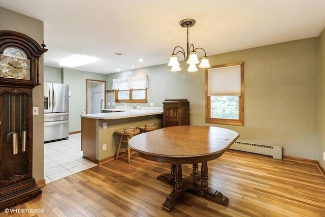 644 N 43rd St, Cumming, IA 50061 - dining area featuring a baseboard heating unit, light wood finished floors, and a chandelier