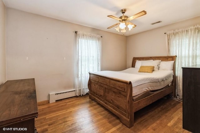 644 N 43rd St, Cumming, IA 50061 - bedroom with baseboard heating, hardwood / wood-style flooring, and a ceiling fan