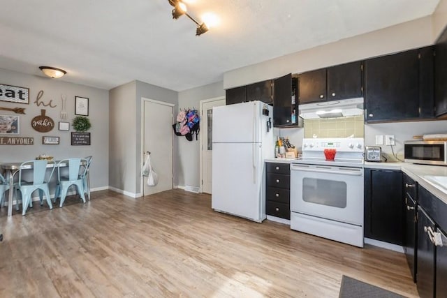 1525 Rapids St, Adel, IA 50003 - kitchen featuring white appliances, under cabinet range hood, light countertops, light wood-type flooring, and dark cabinets