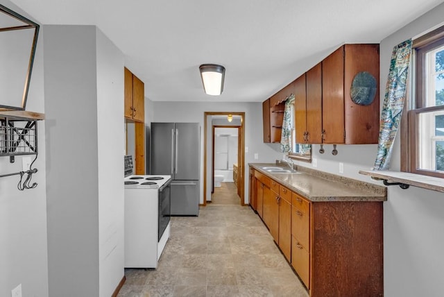 1107 E 12th St N, Newton, IA 50208 - kitchen with white electric range oven, freestanding refrigerator, brown cabinets, and stone finish floors