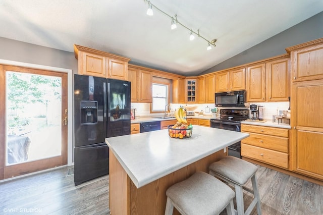 500 NW Valley View Dr, Grimes, IA 50111 - kitchen featuring black appliances, light wood-type flooring, lofted ceiling, light countertops, and a center island