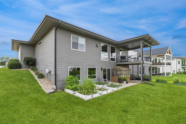 905 NE Badger Ln, Waukee, IA 50263 - rear view of house featuring a lawn, a ceiling fan, a balcony, and a greenhouse