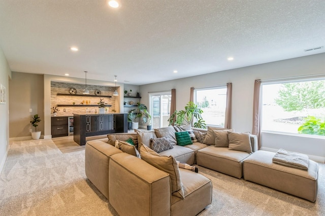 905 NE Badger Ln, Waukee, IA 50263 - living room featuring recessed lighting, light carpet, plenty of natural light, and a textured ceiling