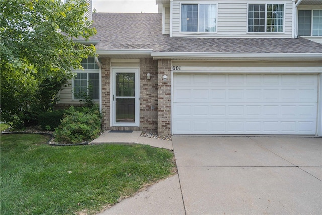 150 S Prairie View Dr Unit 601, West Des Moines, IA 50266 - property entrance featuring concrete driveway, a shingled roof, a garage, brick siding, and a yard