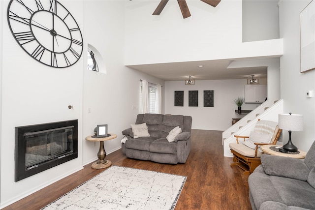 150 S Prairie View Dr Unit 601, West Des Moines, IA 50266 - living room featuring a towering ceiling, wood finished floors, ceiling fan, a glass covered fireplace, and stairs