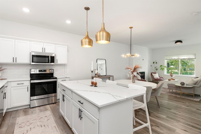 427 Spring Crest Ln, Waukee, IA 50263 - kitchen with stainless steel appliances, light wood-style floors, a center island, open floor plan, and backsplash