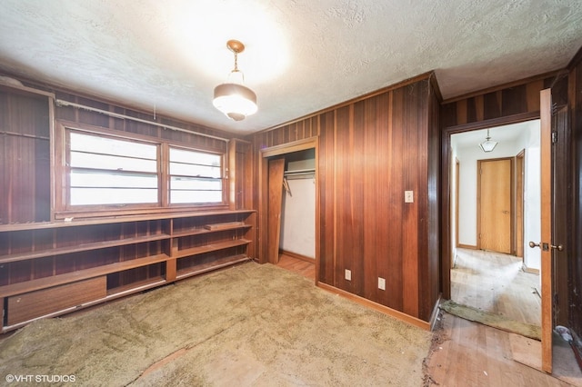 7012 Sunrise Blvd, Windsor Heights, IA 50324 - unfurnished bedroom featuring a closet, a textured ceiling, and wood walls
