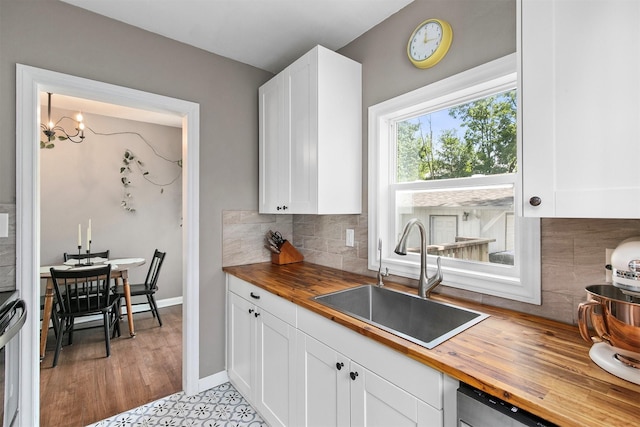 3315 61st St, Des Moines, IA 50322 - kitchen with butcher block countertops, white cabinetry, backsplash, and a chandelier