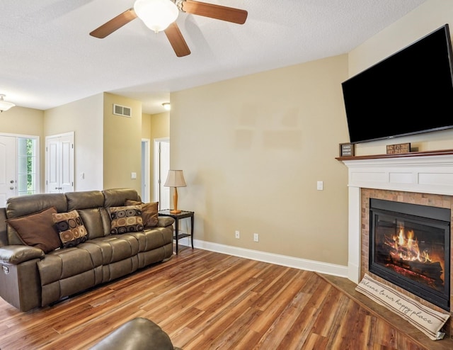 929 Sampson Dr, Nevada, IA 50201 - living room featuring wood finished floors, a fireplace, a ceiling fan, and a textured ceiling