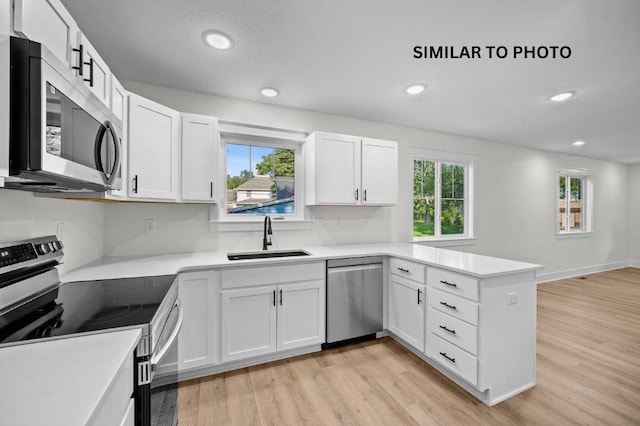 2517 Shaw St, Des Moines, IA 50317 - kitchen featuring stainless steel appliances, a peninsula, light wood-style flooring, white cabinets, and light countertops
