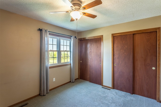 4624 Tamara Ln, West Des Moines, IA 50265 - unfurnished bedroom featuring light carpet, multiple closets, a textured ceiling, and ceiling fan