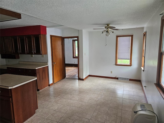 4690 Hubbell Ave, Des Moines, IA 50317 - kitchen with light countertops, a ceiling fan, light tile patterned flooring, healthy amount of natural light, and a textured ceiling