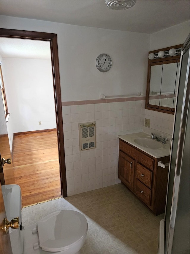 4690 Hubbell Ave, Des Moines, IA 50317 - bathroom featuring tile walls, heating unit, vanity, and a wainscoted wall