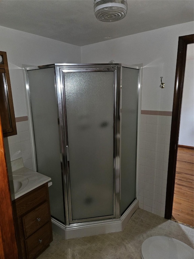 4690 Hubbell Ave, Des Moines, IA 50317 - full bathroom with tile walls, vanity, a shower stall, and a wainscoted wall