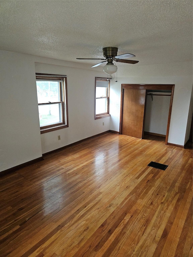 4690 Hubbell Ave, Des Moines, IA 50317 - unfurnished bedroom featuring wood finished floors, a textured ceiling, a ceiling fan, and a closet