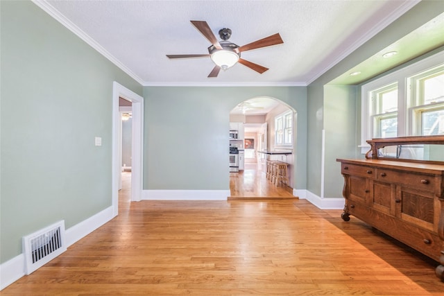 2521 40th St, Des Moines, IA 50310 - spare room with arched walkways, a ceiling fan, light wood-style floors, crown molding, and a textured ceiling