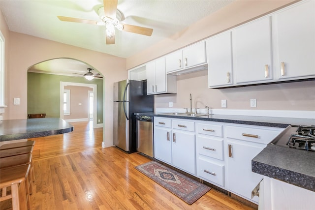 2521 40th St, Des Moines, IA 50310 - kitchen featuring stainless steel appliances, a ceiling fan, arched walkways, white cabinets, and dark countertops