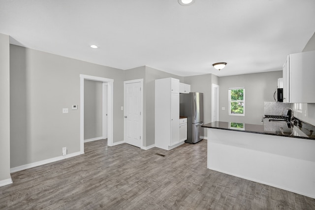 1728 NW Dr, Des Moines, IA 50310 - kitchen featuring freestanding refrigerator, wood finished floors, white cabinets, dark countertops, and a peninsula