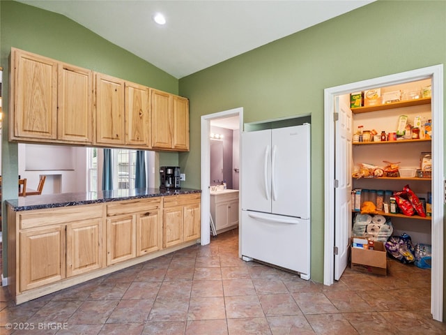 623 N Main St, Stuart, IA 50250 - kitchen with freestanding refrigerator, light brown cabinets, vaulted ceiling, and dark stone counters