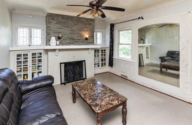 1118 Euclid Ave, Des Moines, IA 50313 - living area featuring a fireplace, ceiling fan, a textured ceiling, and plenty of natural light