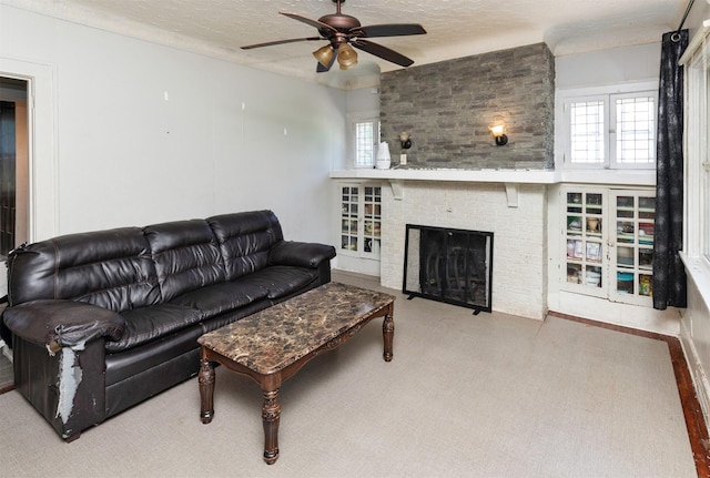 1118 Euclid Ave, Des Moines, IA 50313 - living room with ceiling fan, a textured ceiling, carpet flooring, and a brick fireplace