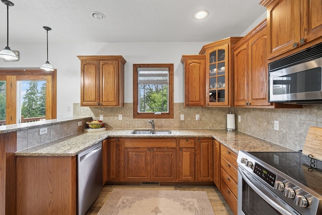 4309 129th St, Urbandale, IA 50323 - kitchen featuring stainless steel appliances, brown cabinets, light stone countertops, a peninsula, and glass insert cabinets