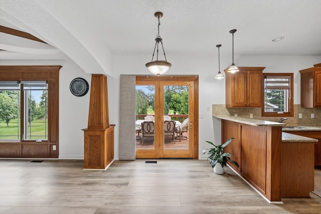 4309 129th St, Urbandale, IA 50323 - kitchen with healthy amount of natural light, brown cabinetry, and decorative backsplash