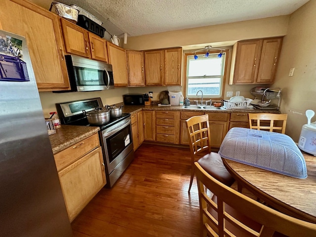 3923 15th St, Des Moines, IA 50313 - kitchen with stainless steel appliances, dark wood-style flooring, a textured ceiling, and dark countertops
